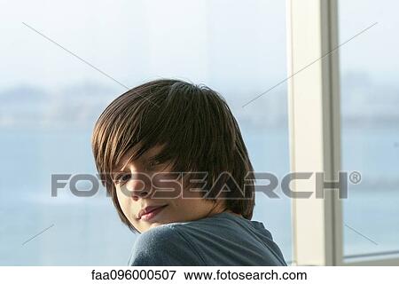 Stock Photo - Teenage boy smiling over shoulder, portrait. Fotosearch