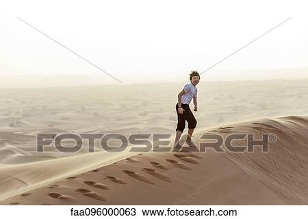 Teenage boy walking on desert dune View Large Photo Image Stock Image - Teenage boy walking on desert dune. Fotosearch