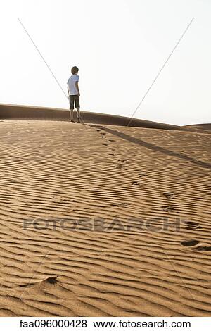 Teenage boy walking up desert dune, rear view View Large Photo Image Stock Photo - Teenage boy walking up desert dune, rear view. Fotosearch
