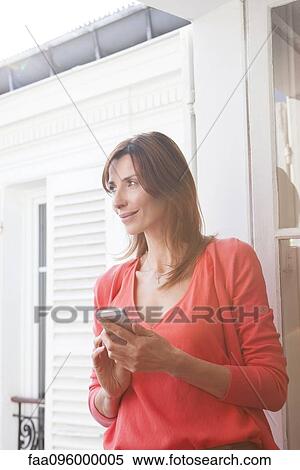 Stock Photography - Woman by open window looking at view. Fotosearch
