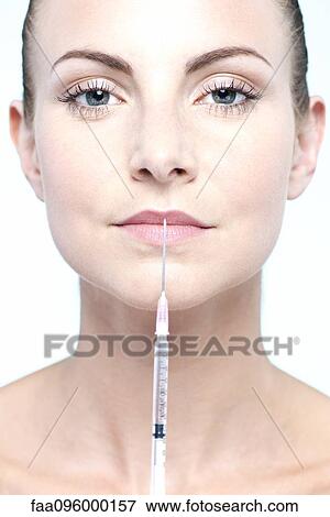 Stock Photo - Woman holding up syringe. Fotosearch