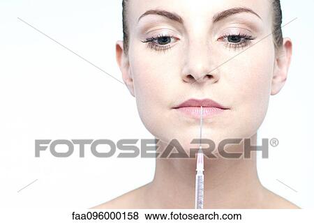 Stock Photo - Woman holding up syringe. Fotosearch