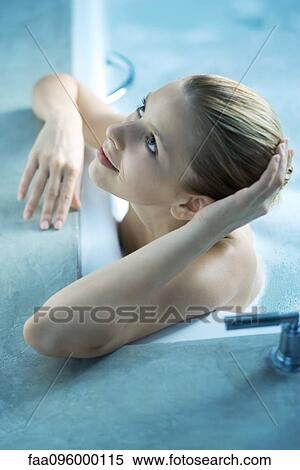 Stock Photography - Woman in bath tub, leaning on side of tub, looking up. Fotosearch