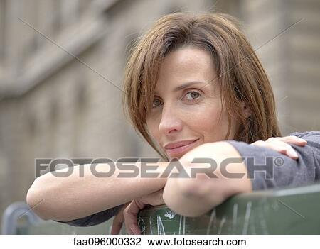 Stock Image - Woman leaning against railing outdoors, portrait. Fotosearch