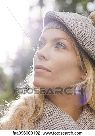 Stock Image - Woman outdoors, looking up in thought, portrait. Fotosearch