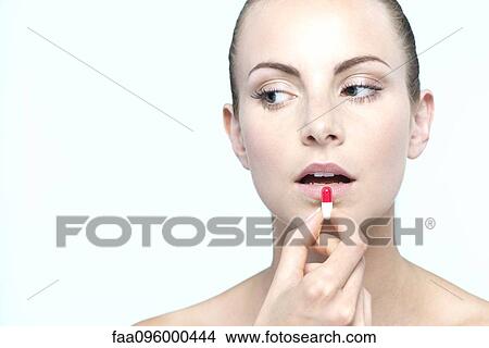 Picture - Woman preparing to take capsule. Fotosearch
