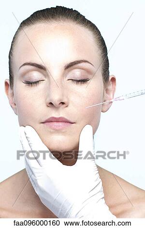 Stock Image - Woman receiving collagen injection. Fotosearch