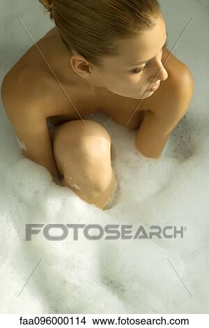 Woman sitting in bubble bath, looking away, high angle view View Large Photo Image Picture - Woman sitting in bubble bath, looking away, high angle view. Fotosearch