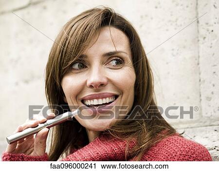 Woman smoking electronic cigarette, smiling View Large Photo Image Stock Image - Woman smoking electronic cigarette, smiling. Fotosearch