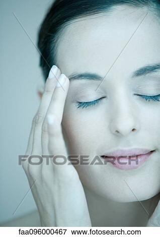 Stock Photo - Woman touching face, eyes closed, portrait. Fotosearch