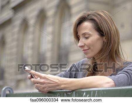 Woman using smartphone outdoors View Large Photo Image Picture - Woman using smartphone outdoors. Fotosearch