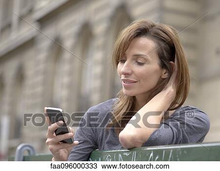 Woman using smartphone outdoors View Large Photo Image Stock Image - Woman using smartphone outdoors. Fotosearch