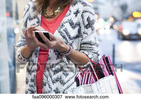 Woman using smartphone while shopping View Large Photo Image Stock Photo - Woman using smartphone while shopping. Fotosearch