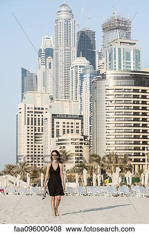 Woman walking on beach with skyscrapers in background, Dubai, United Arab Emirates View Large Photo Image Stock Photo - Woman walking on beach with skyscrapers in background, Dubai, United Arab Emirates. Fotosearch