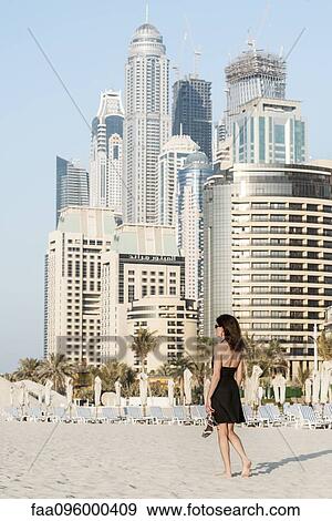 Woman walking on beach with skyscrapers in background, Dubai, United Arab Emirates View Large Photo Image Stock Photo - Woman walking on beach with skyscrapers in background, Dubai, United Arab Emirates. Fotosearch