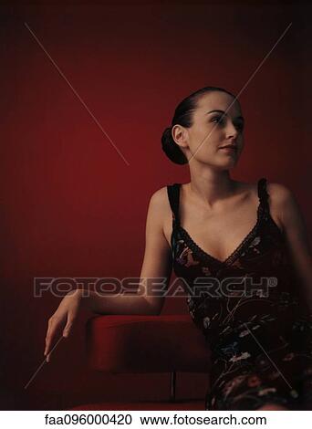 Woman wearing dress, sitting in chair, looking away View Large Photo Image Stock Image - Woman wearing dress, sitting in chair, looking away. Fotosearch