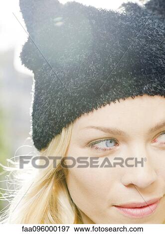 Stock Photo - Woman wearing knit hat, looking away in thought, portrait. Fotosearch
