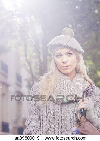 Stock Image - Woman wearing knit hat walking outdoors, portrait. Fotosearch