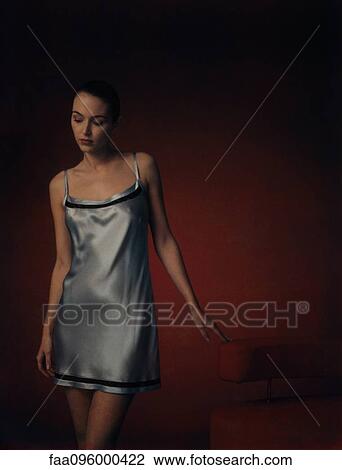 Stock Image - Woman wearing nightgown, looking down, portrait. Fotosearch
