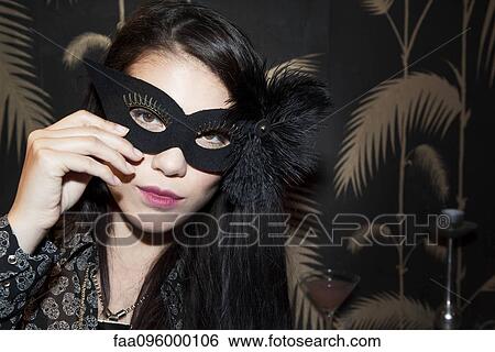 Stock Photograph - Woman wearing party mask, portrait. Fotosearch
