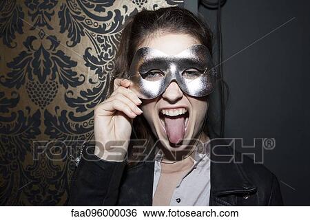 Woman wearing party mask, sticking out tongue, portrait View Large Photo Image Stock Photograph - Woman wearing party mask, sticking out tongue, portrait. Fotosearch