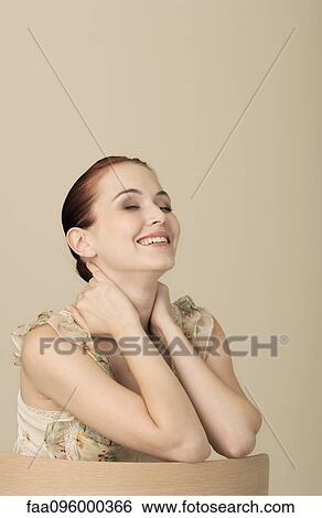 Stock Photograph - Woman wearing ruffly dress, eyes closed, laughing, portrait. Fotosearch
