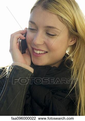 Stock Image - Young woman outdoors speaking on cell phone. Fotosearch