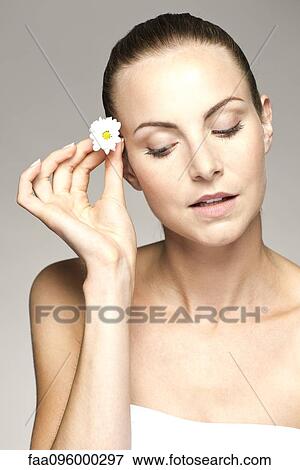 Young woman placing flower in her hair View Large Photo Image Stock Photo - Young woman placing flower in her hair. Fotosearch
