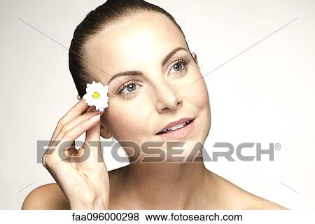 Stock Photo - Young woman placing flower in her hair. Fotosearch