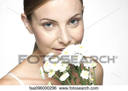 Stock Photograph - Young woman smelling bouquet of daisies. Fotosearch