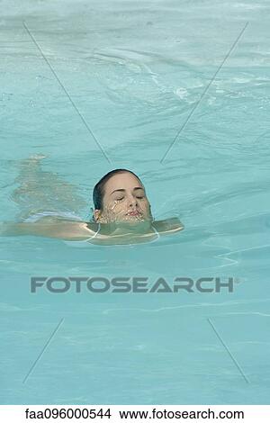Young woman swimming in swimming pool, eyes closed View Large Photo Image Picture - Young woman swimming in swimming pool, eyes closed. Fotosearch