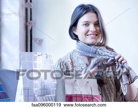 Stock Photo - Young woman trying on new scarf. Fotosearch