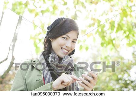 Young woman using smartphone outdoors View Large Photo Image Stock Photo - Young woman using smartphone outdoors. Fotosearch
