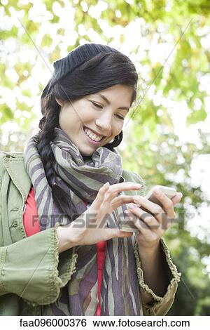 Young woman using smartphone outdoors View Large Photo Image Stock Photograph - Young woman using smartphone outdoors. Fotosearch