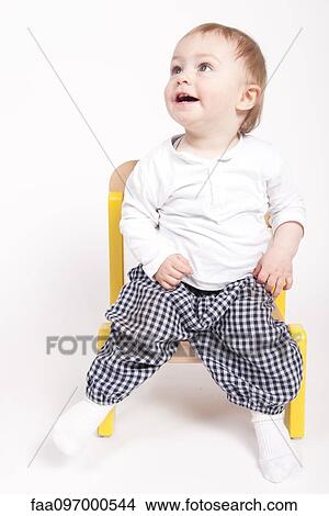 Picture - Baby boy sitting in chair, looking up, portrait. Fotosearch