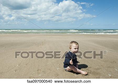 Stock Image - Baby sitting on beach. Fotosearch