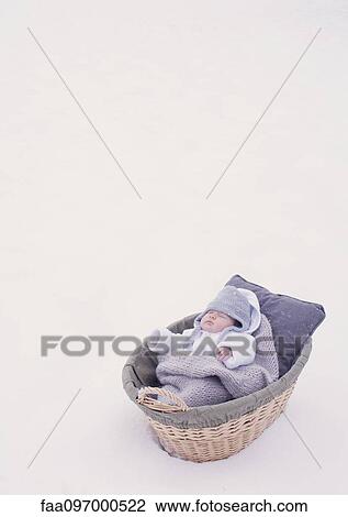 Stock Image - Baby sleeping in bassinet in snow. Fotosearch