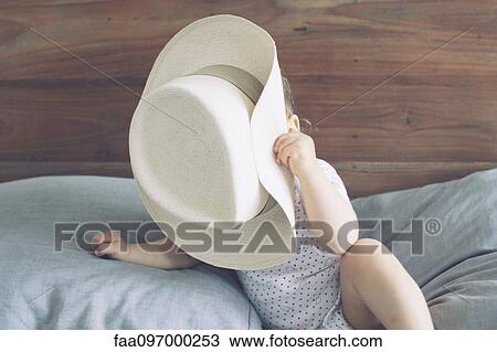 Stock Image - Baby with face obscured by oversized hat. Fotosearch