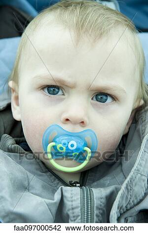 Stock Image - Baby with pacifier in mouth, portrait. Fotosearch