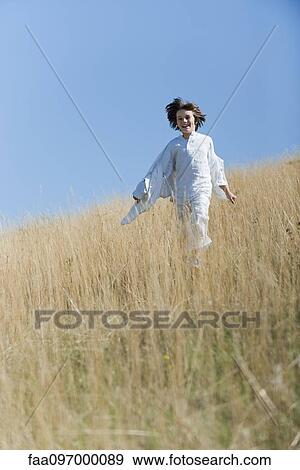 Stock Photo - Boy running through tall grass. Fotosearch