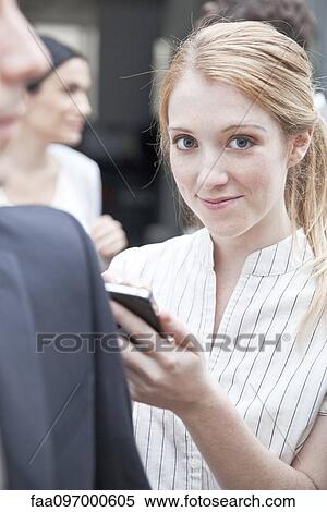 Busimesswoman checking smartphone while on the move View Large Photo Image Stock Photography - Busimesswoman checking smartphone while on the move. Fotosearch