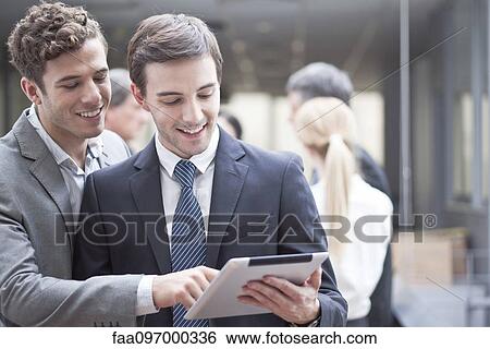 Business colleagues looking at digital tablet together View Large Photo Image Stock Photograph - Business colleagues looking at digital tablet together. Fotosearch
