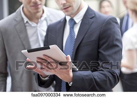 Picture - Businessman showing colleague digital tablet. Fotosearch