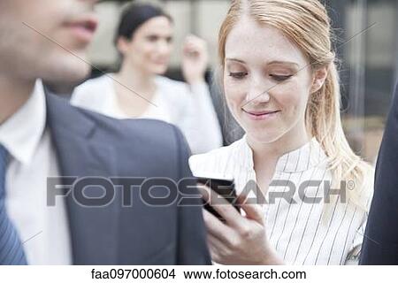 Picture - Businesswoman checking smartphone while on the move. Fotosearch