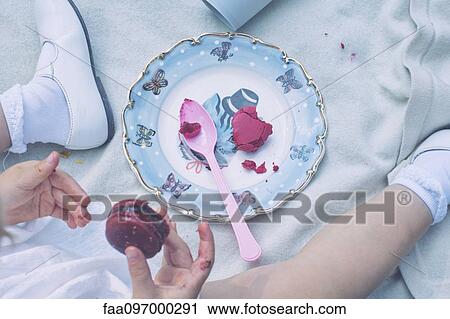 Stock Image - Child with messy fingers eating macaroon. Fotosearch