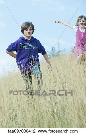 Stock Image - Children playing on grassy hillside. Fotosearch
