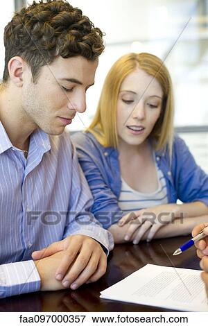 Stock Photo - Clients reviewing contract with advisor. Fotosearch
