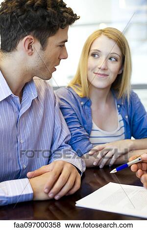 Stock Photo - Clients reviewing contract with advisor. Fotosearch