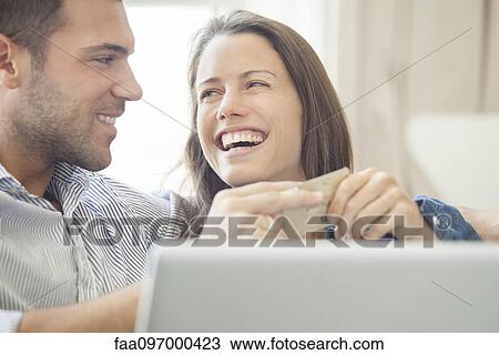Stock Image - Couple at home shopping online together. Fotosearch