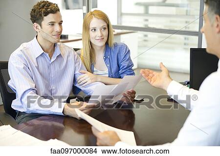 Couple discussing paperwork with advisor View Large Photo Image Picture - Couple discussing paperwork with advisor. Fotosearch